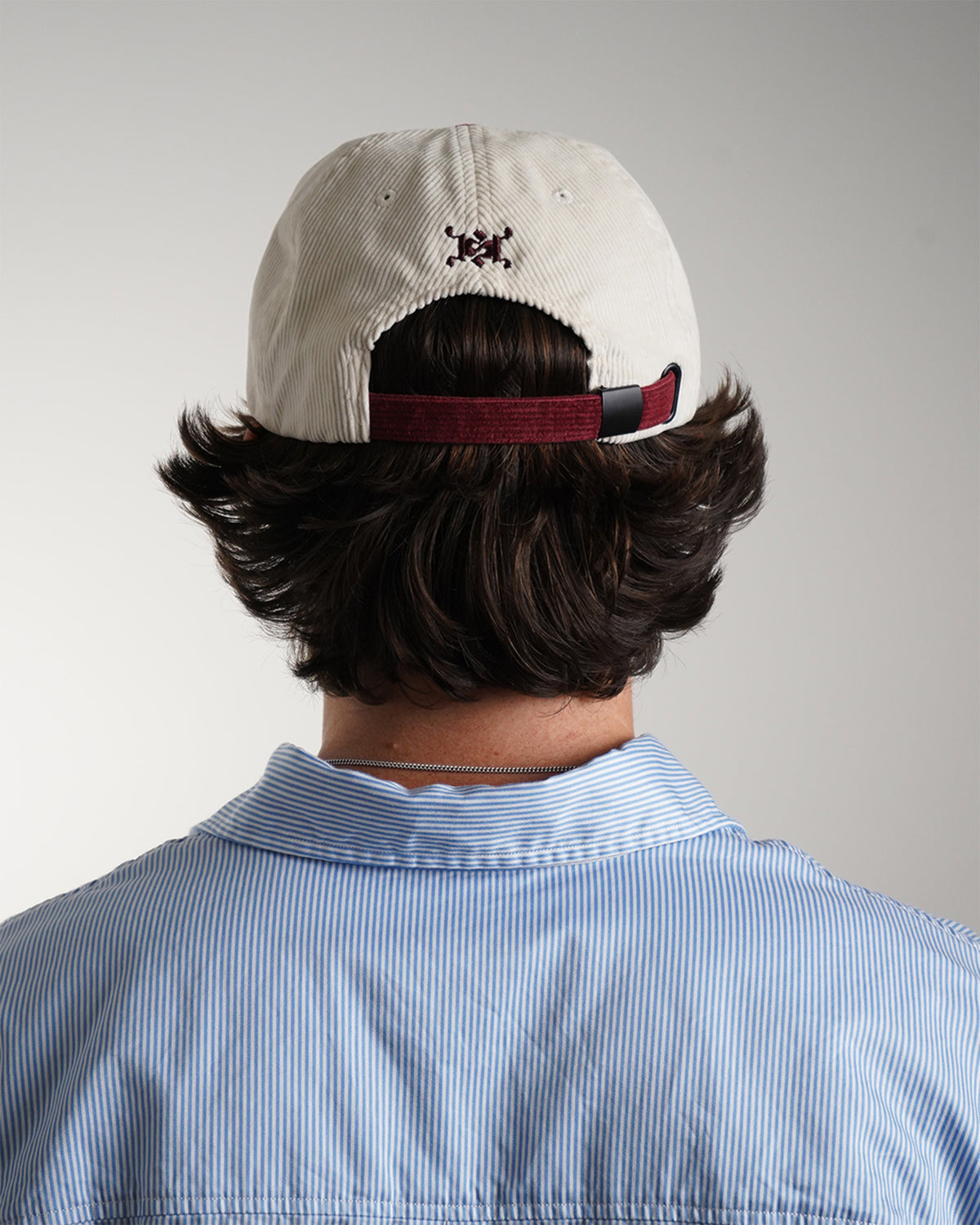 Back of the cream corduroy Easy Come Easy Go Hat with burgundy adjustable strap and embroidered logo, on model