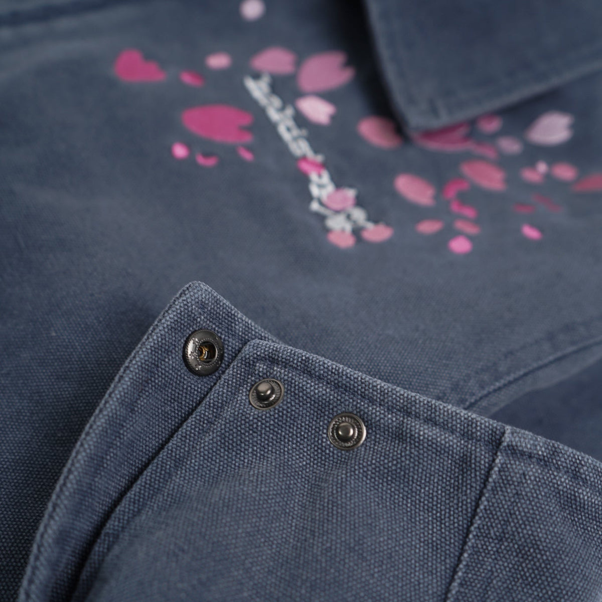 Close-up of a navy blue garment with pink floral patterns and button details.