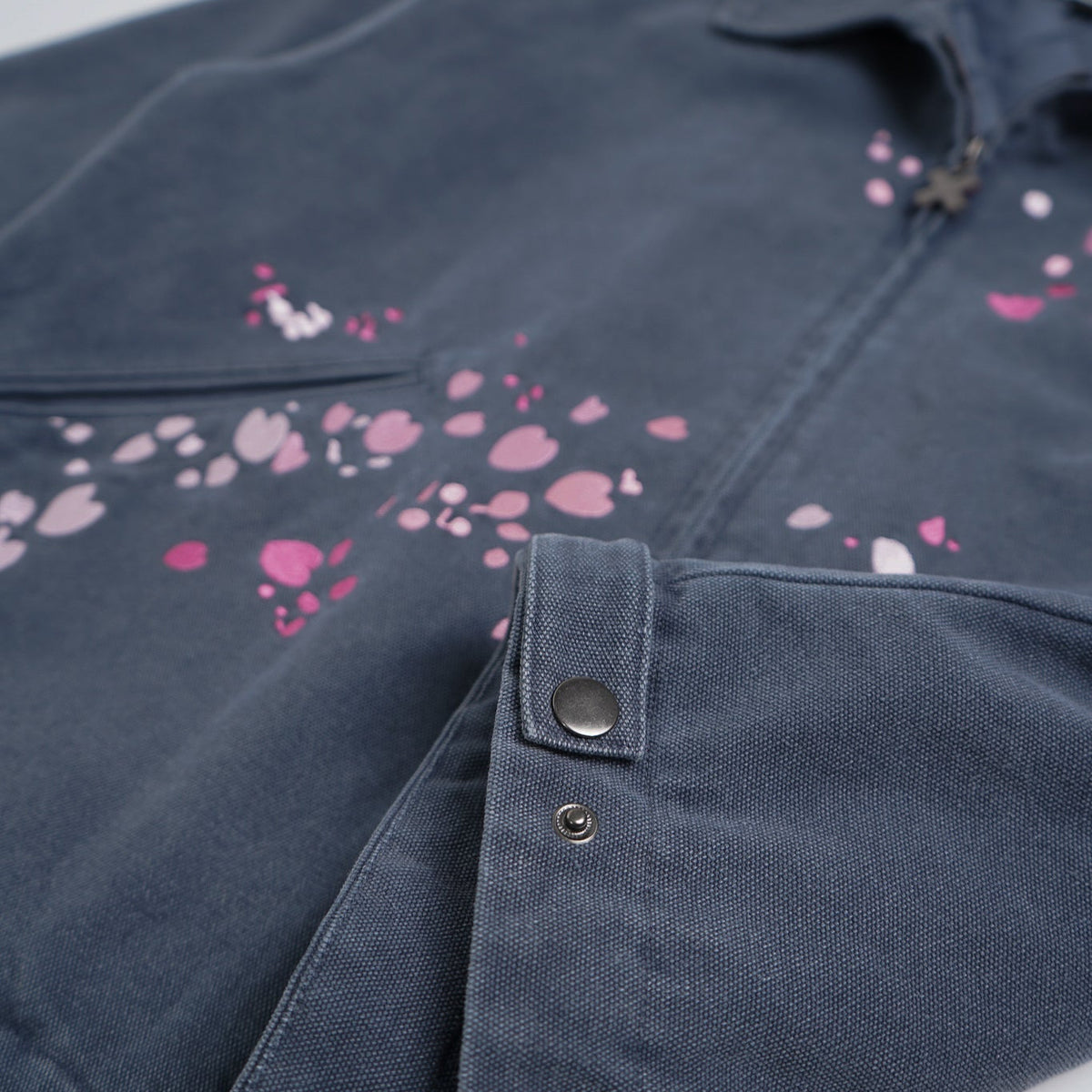 Folded denim jacket with pink floral patterns on a light gray background