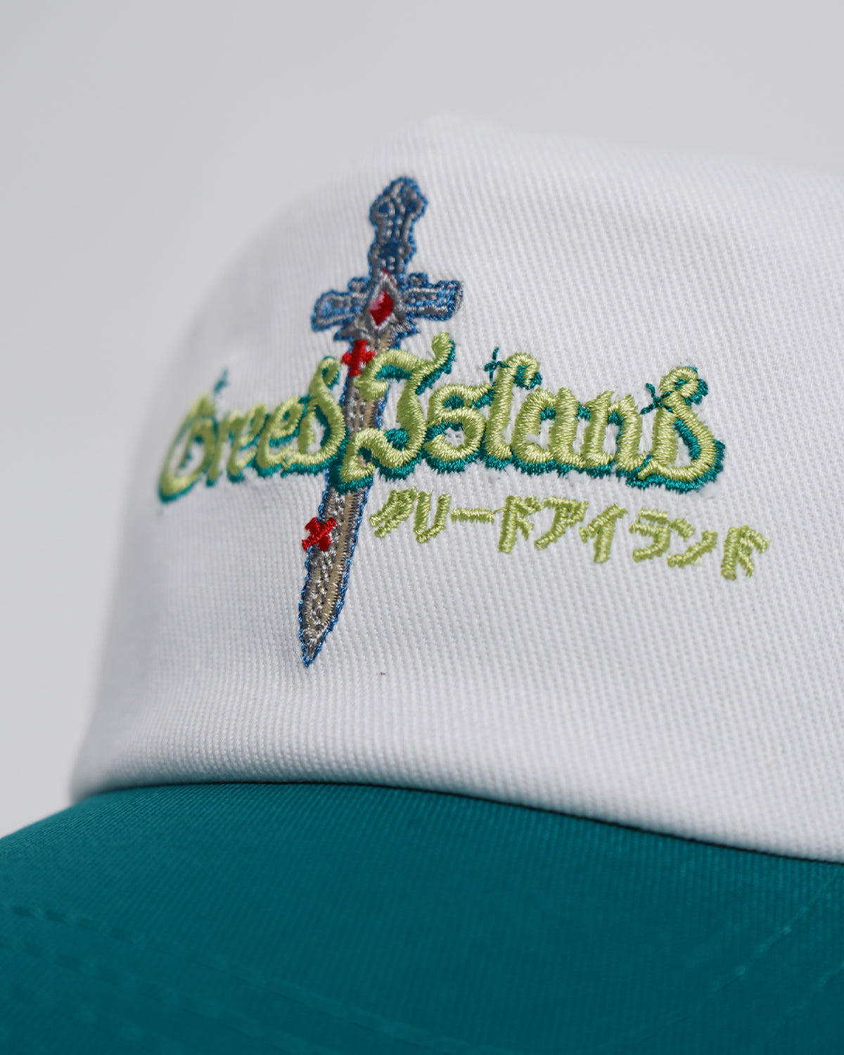 White and teal Greed Island Hat with embroidered logo, side angle view