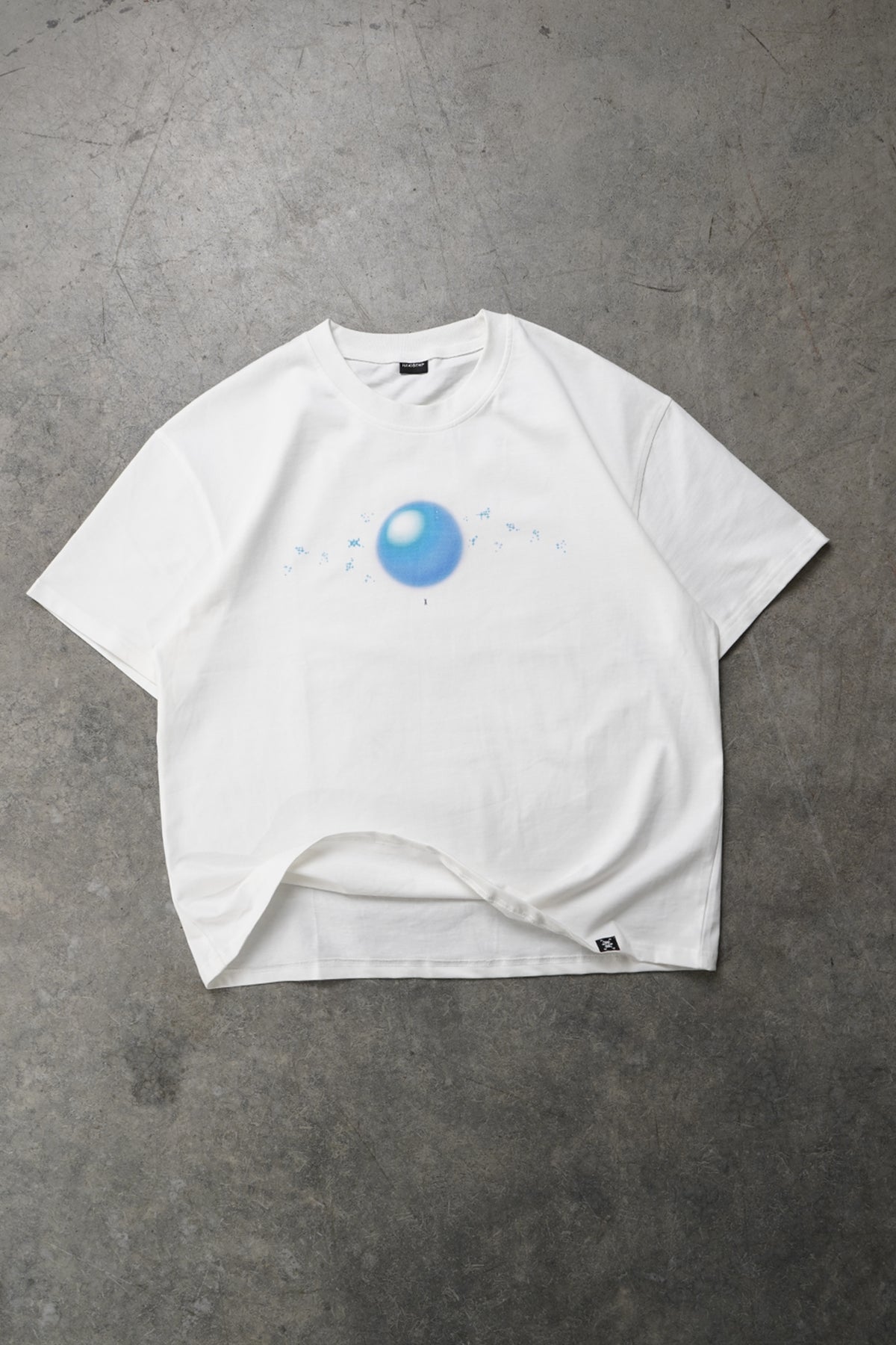 Flat lay front view of the white Spirit Bomb Tee with a blurry blue orb graphic and small blue speckles across the chest