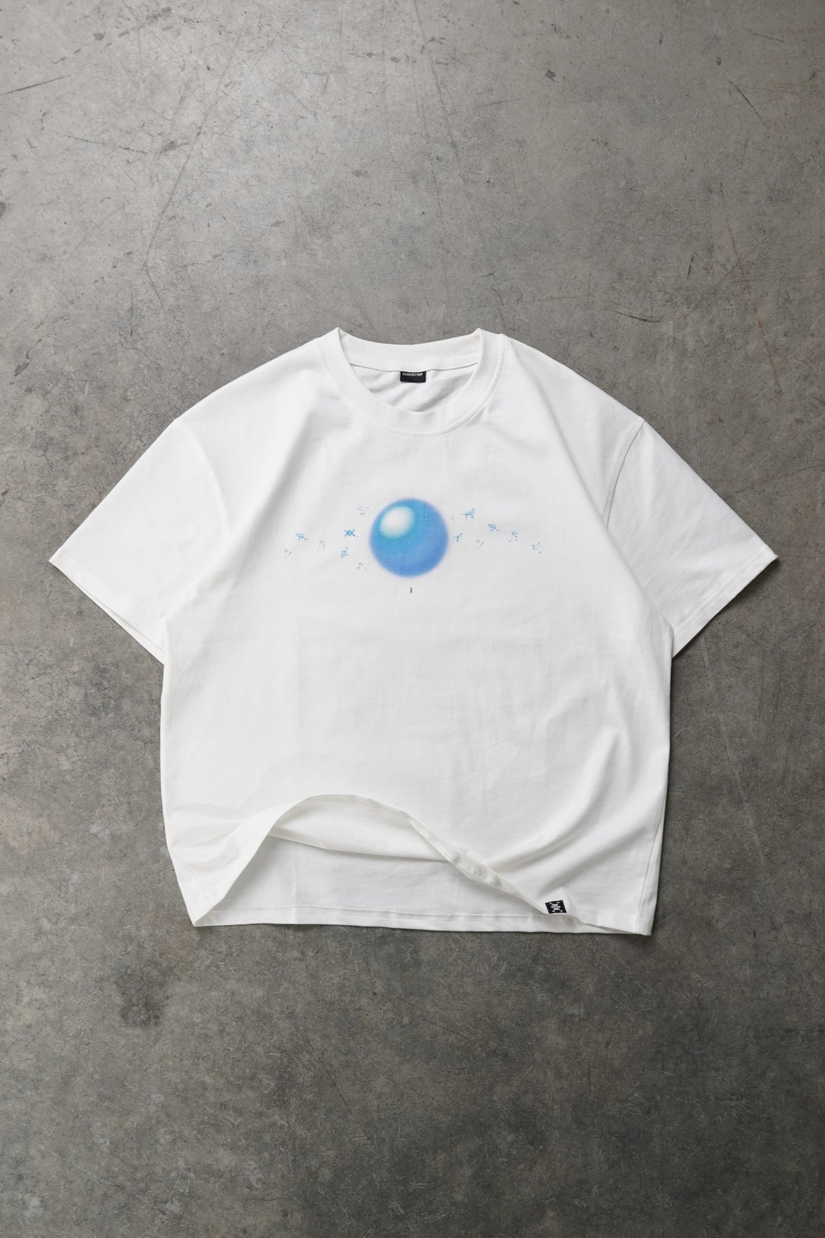 Flat lay front view of the white Dragonball 40th Anniversary Tee Bundle tee with a small blue glossy orb graphic and tiny blue sparkles on the chest