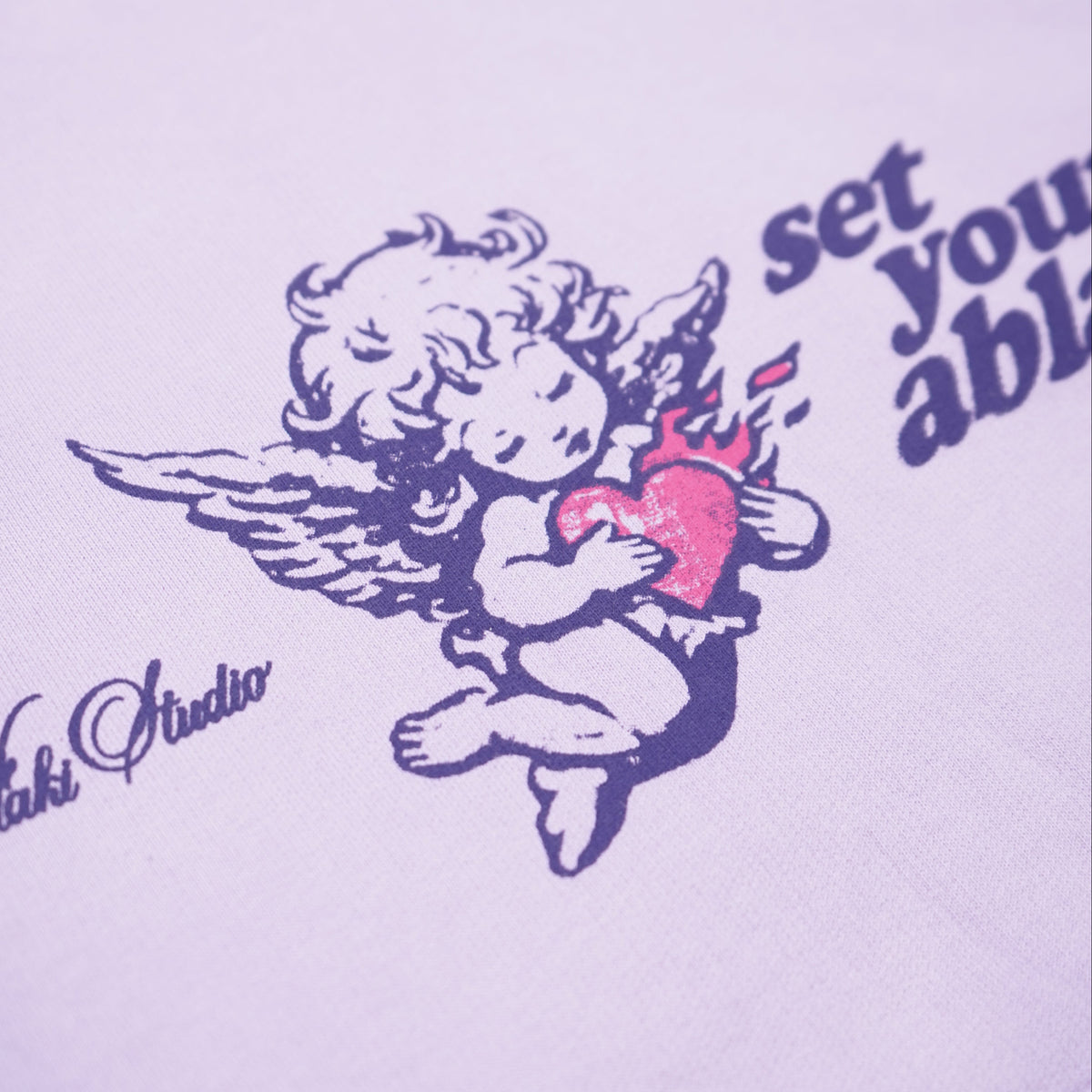 White sweatshirt with angel graphic and text on a light purple background
