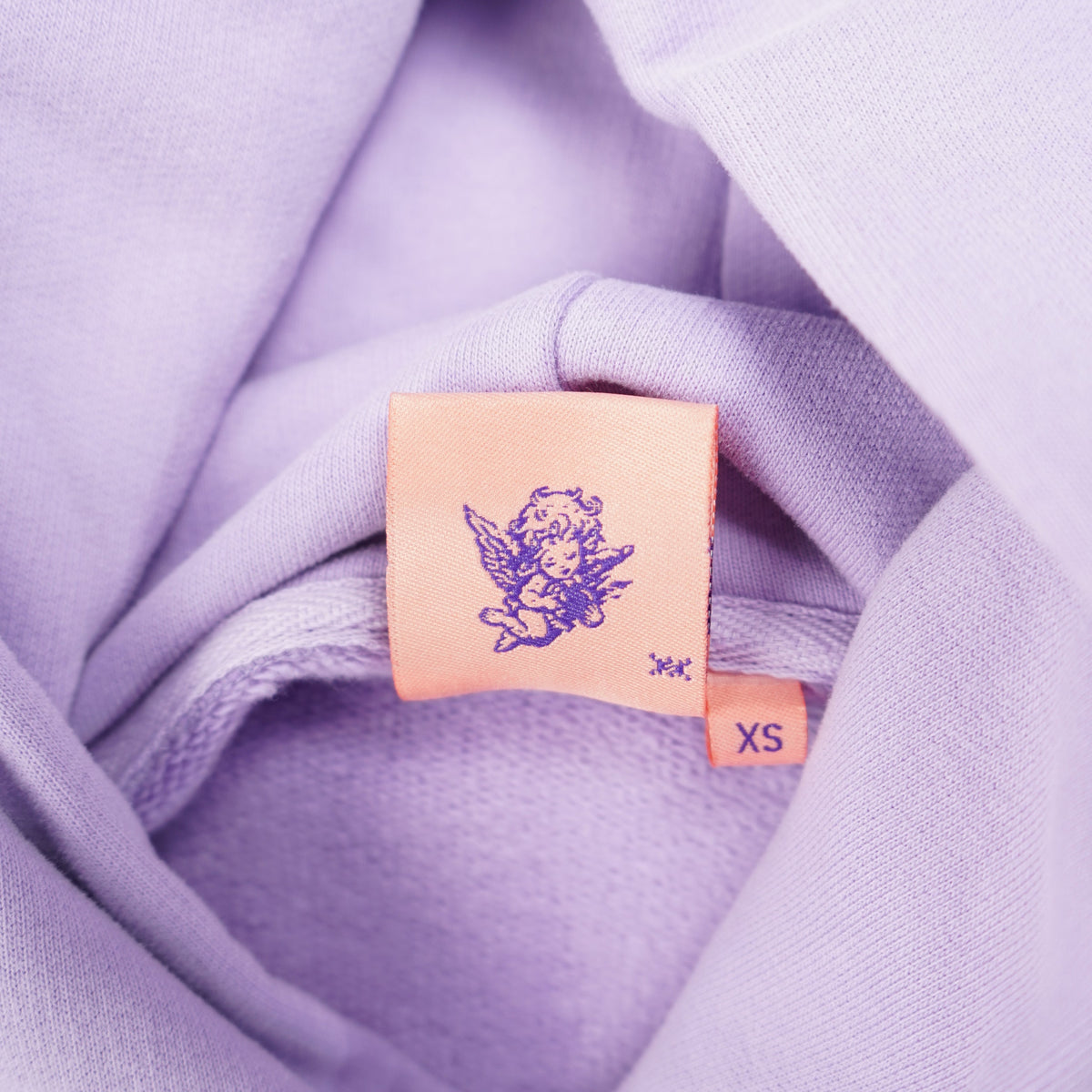 Close-up of a lavender fabric with a small rectangular tag featuring a logo.