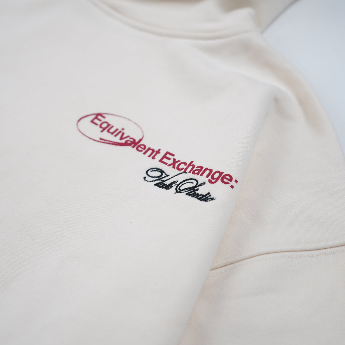 Beige hoodie with red and black text logo on a white background