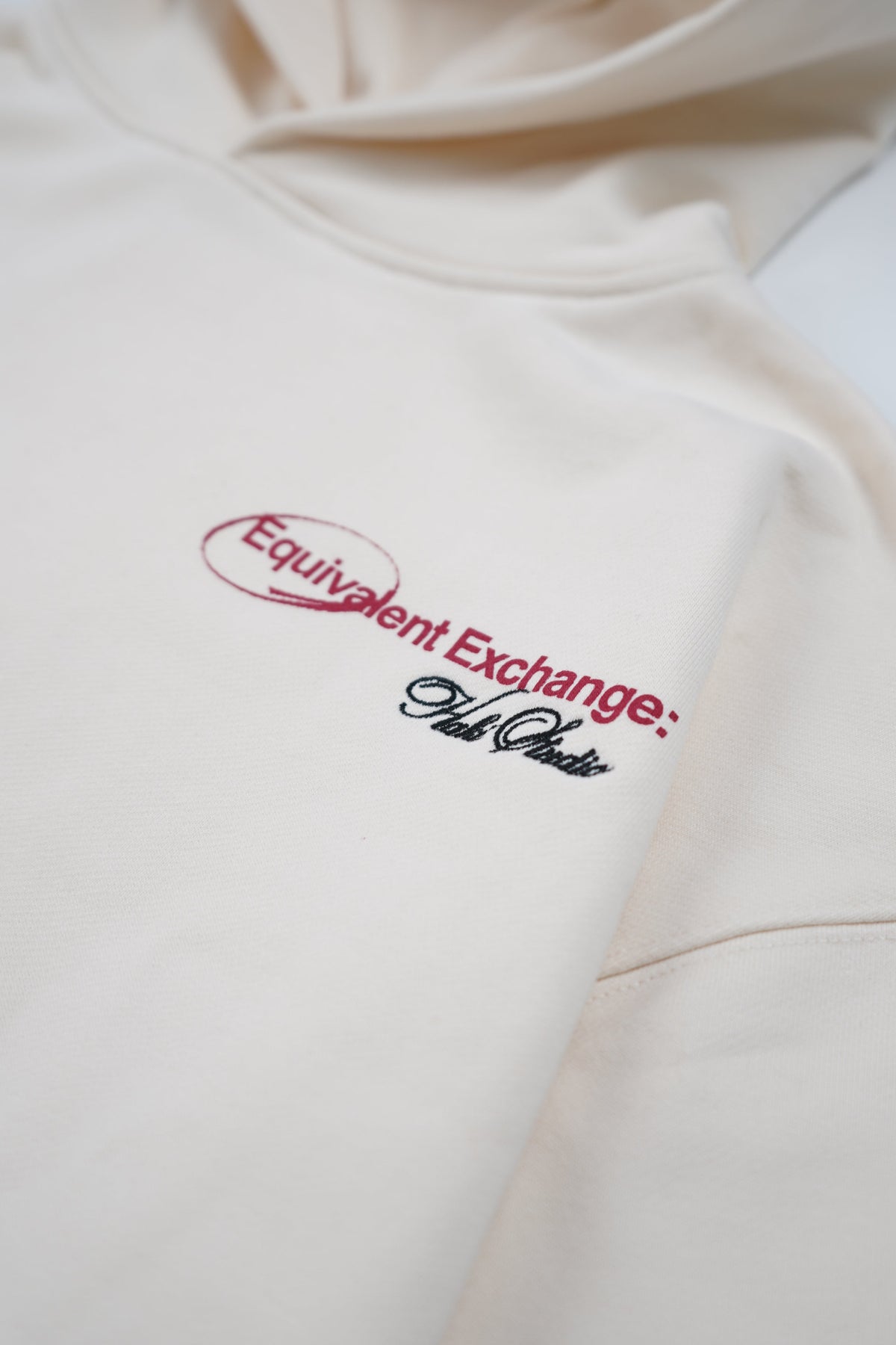 Beige hoodie with red and black text logo on a white background