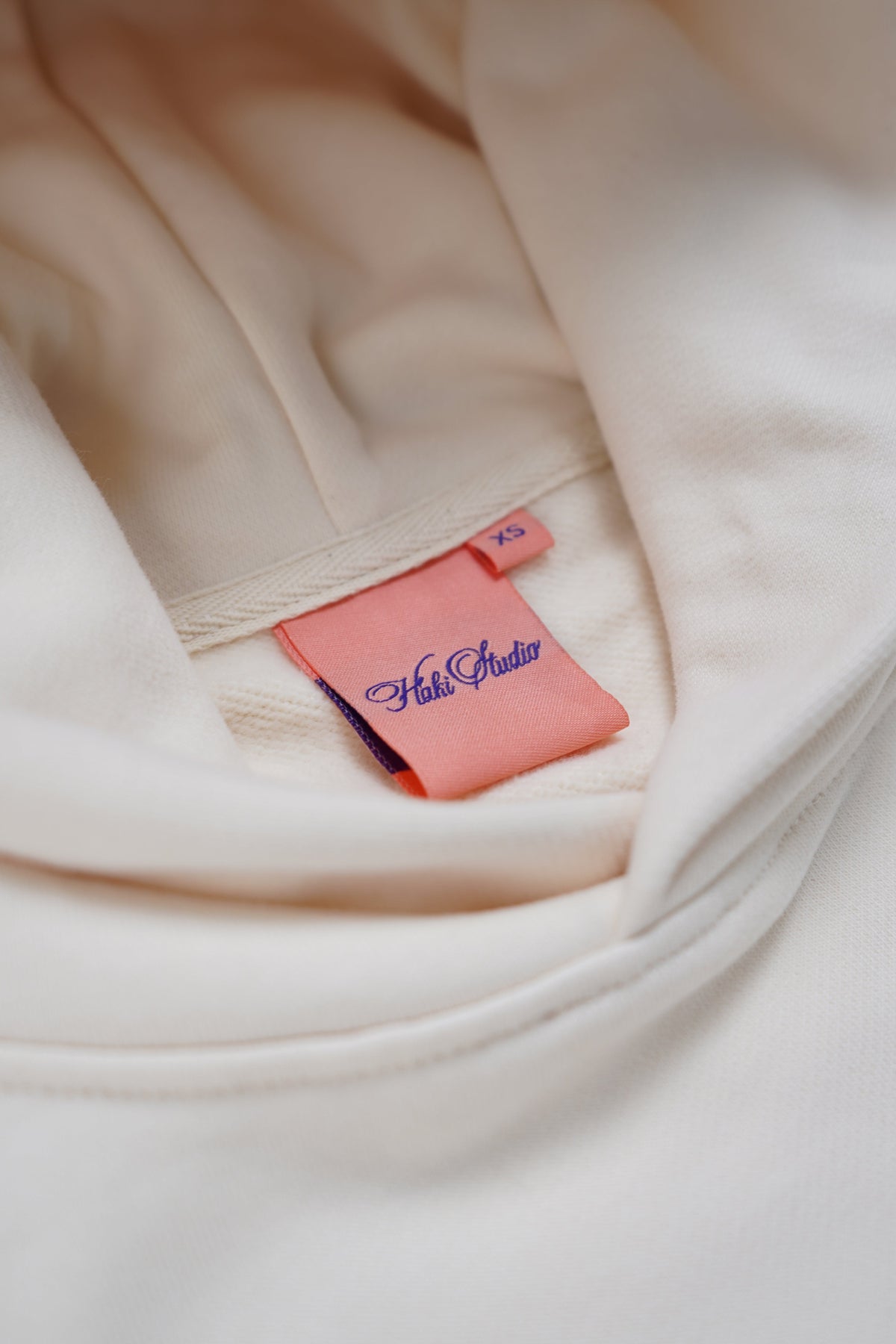 Close-up of a beige garment with a pink tag featuring text on a light background