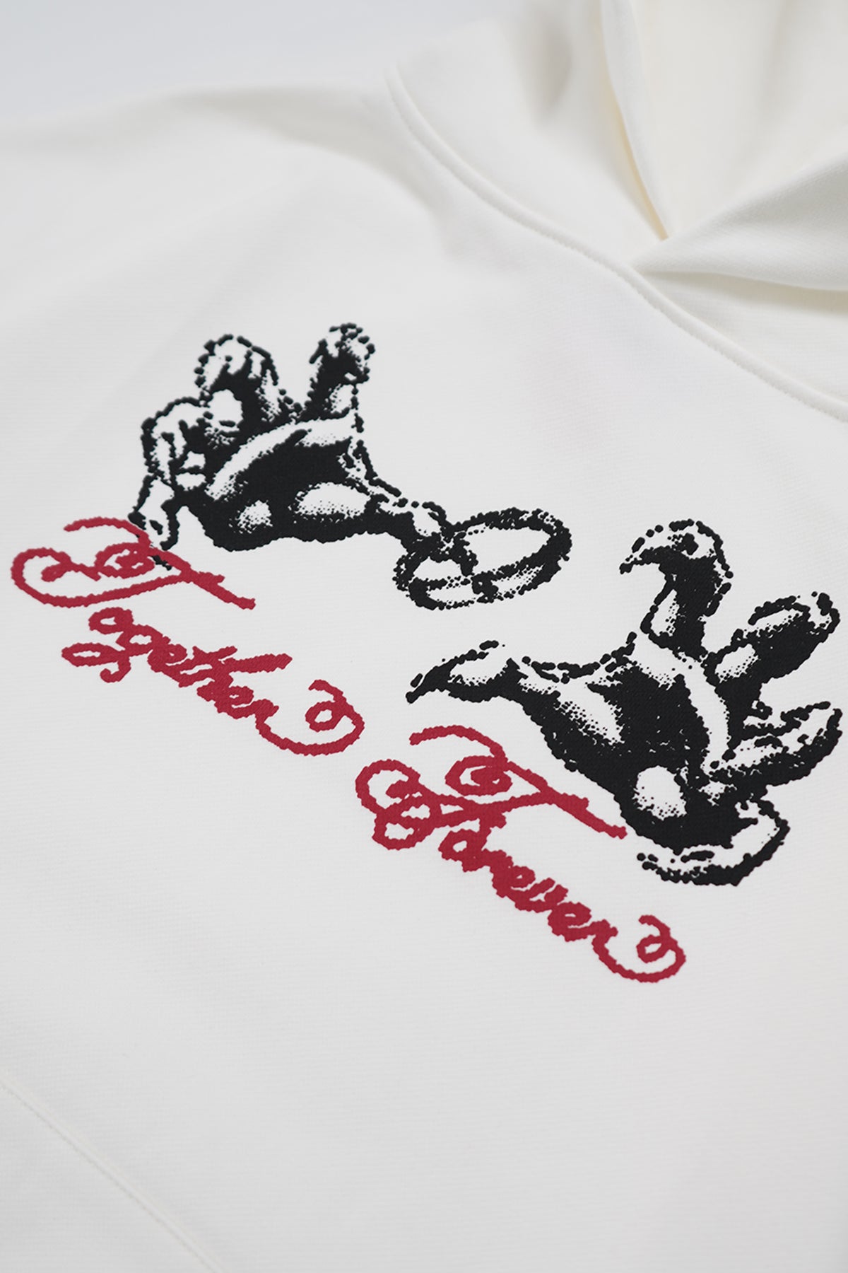 Close-up of the cream Together Forever Hoodie front, showing red script text reading "Together Forever" beneath two black halftone cherub figures