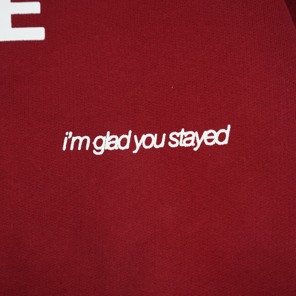 Red fabric with white text 'i'm glad you stayed' and partially visible brand name.