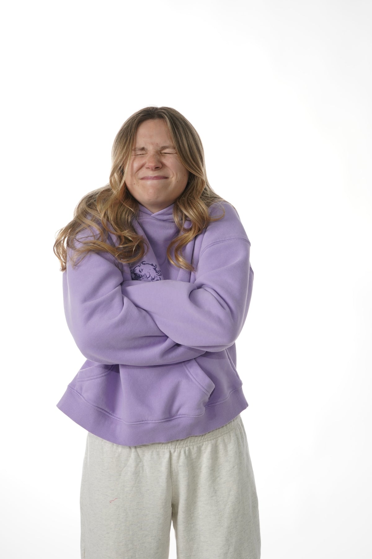 Person wearing a purple hoodie and light-colored pants on a white background