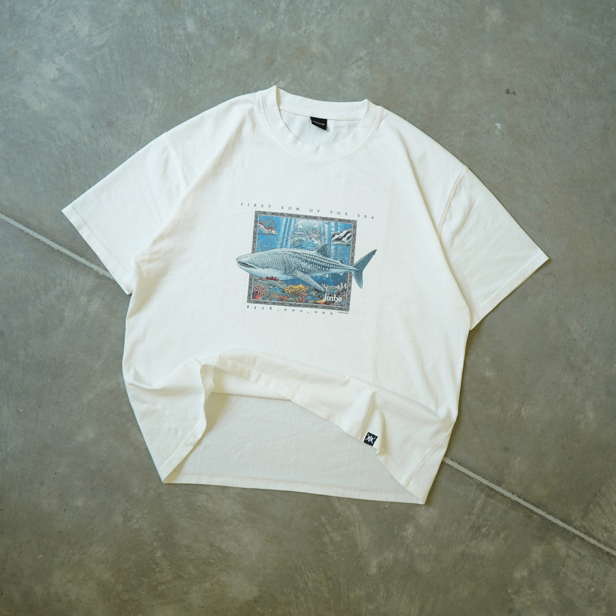 White t-shirt with graphic design on a gray concrete surface
