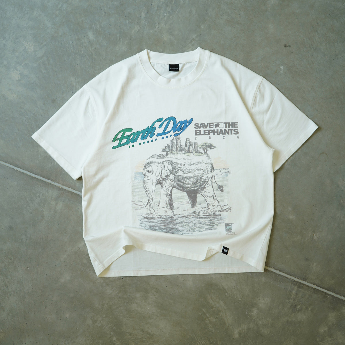 White t-shirt with graphic design and text on a gray concrete surface