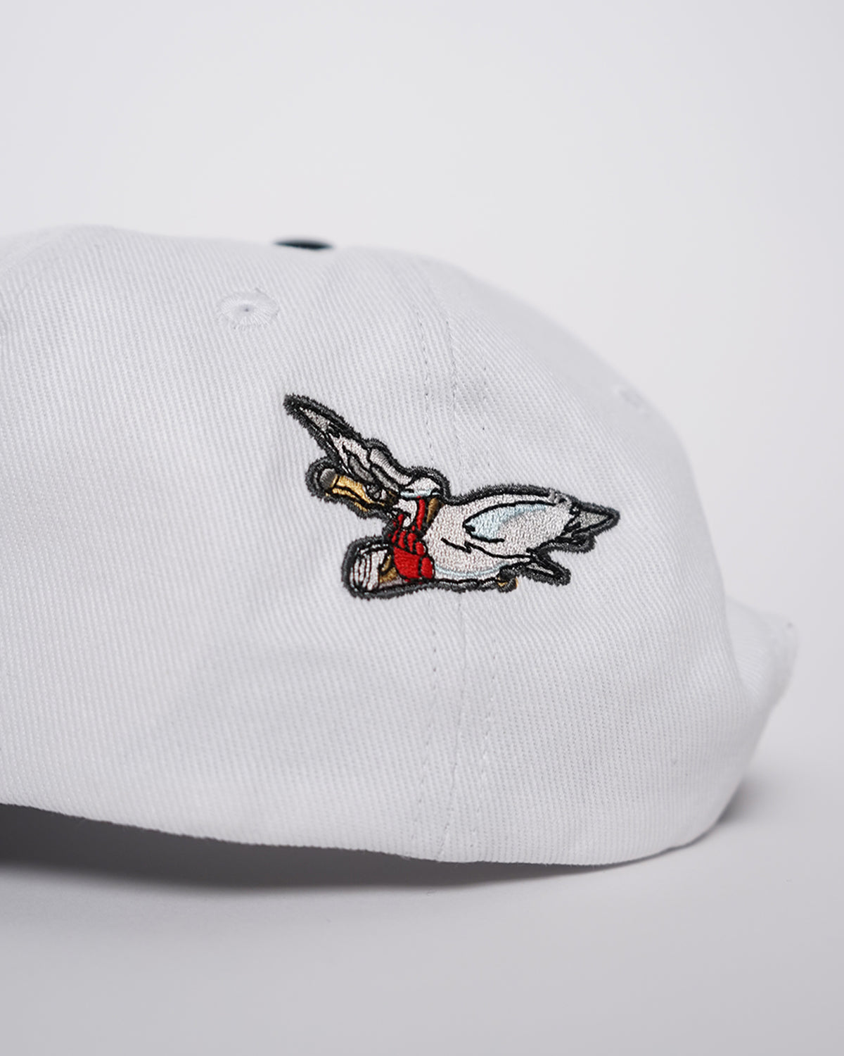 Big News! Hat in white with black brim, side view showing embroidered flying bird graphic