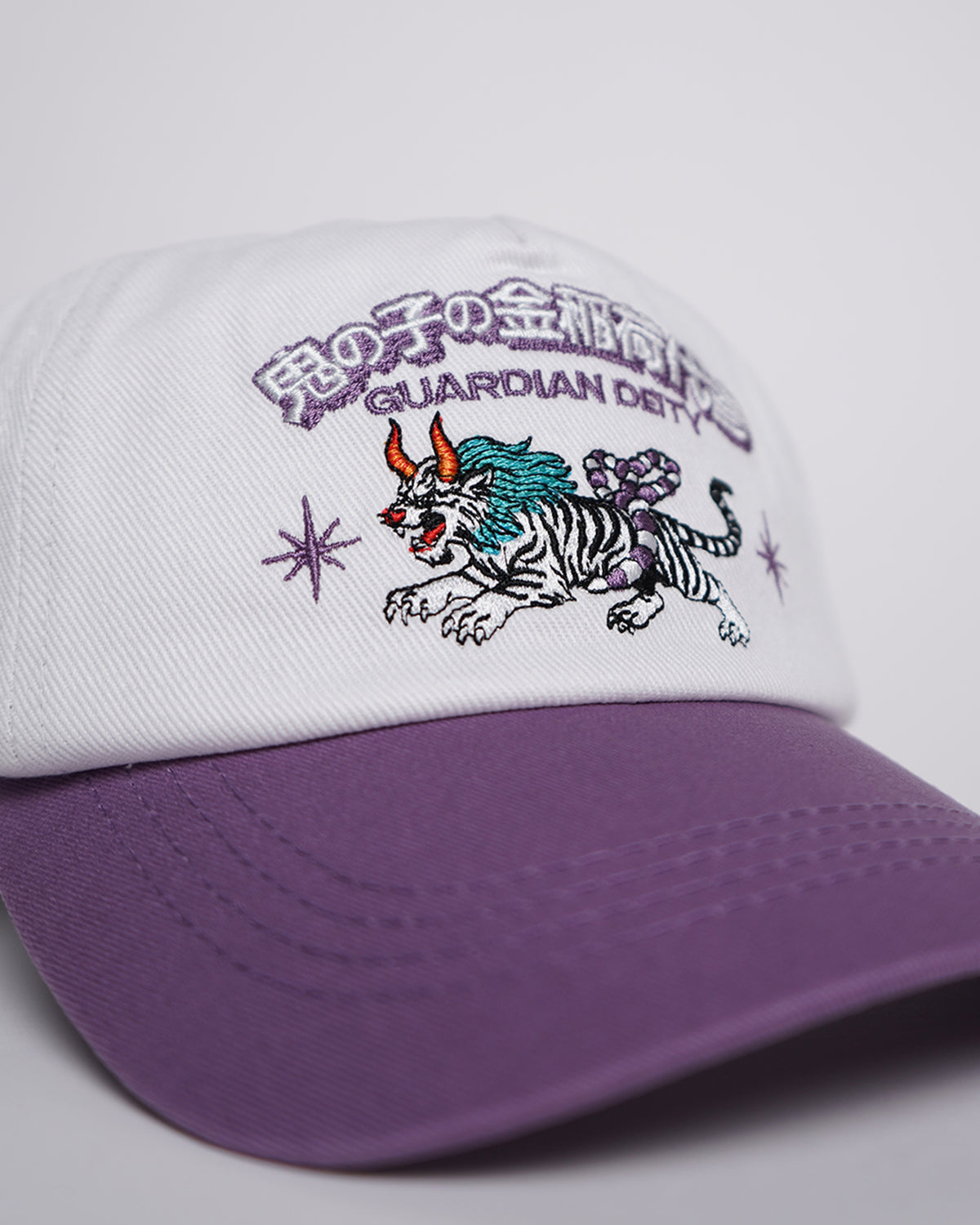Guardian Deity Hat in white and purple with embroidered mythical creature graphic, side angle view