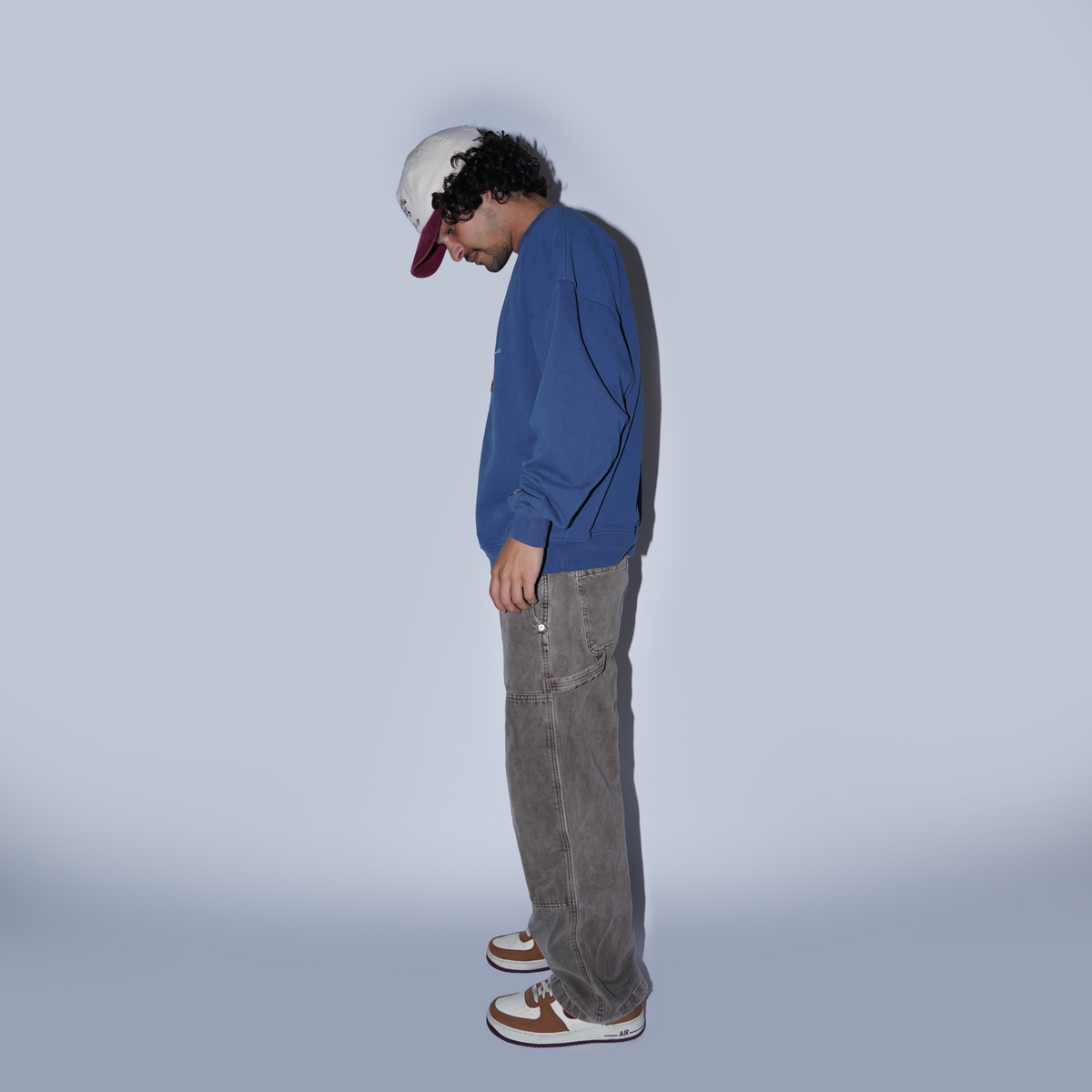 Person wearing a blue sweatshirt and gray pants against a plain background